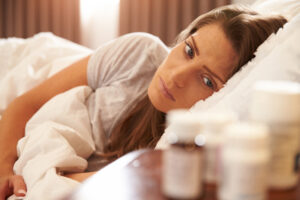 Unhappy Woman Looking At Medication On Bedside Table | Matsimela Home Spa